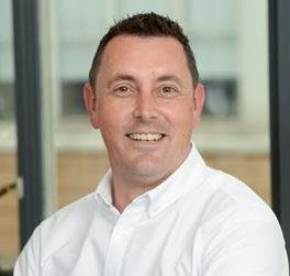 Smiling man in a white shirt, indoors.