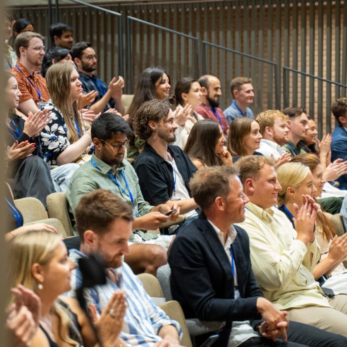 Audience members sitting in a theater, clapping in appreciation.