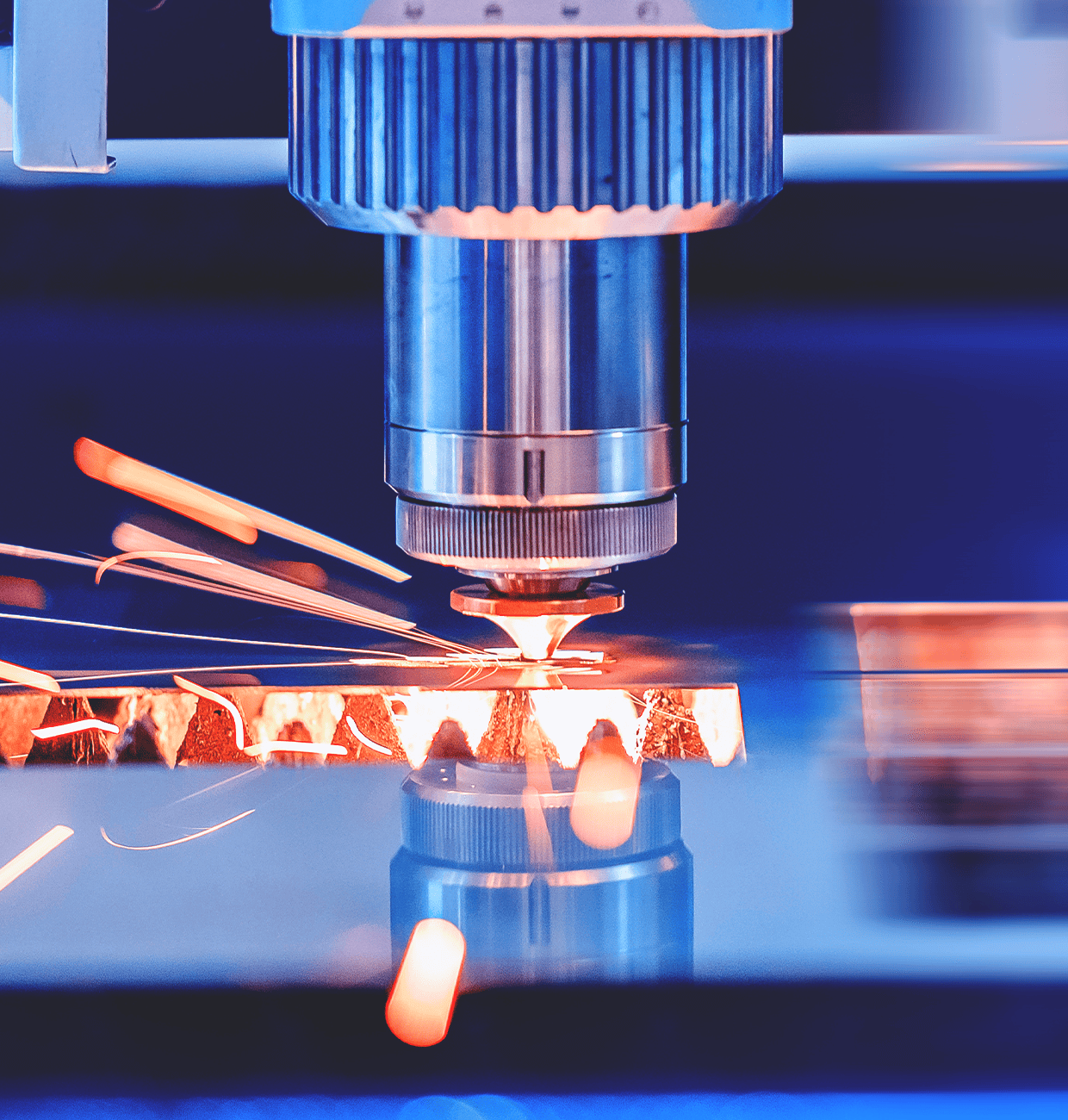 A close-up of a laser cutting machine cutting through metal, sparks flying.