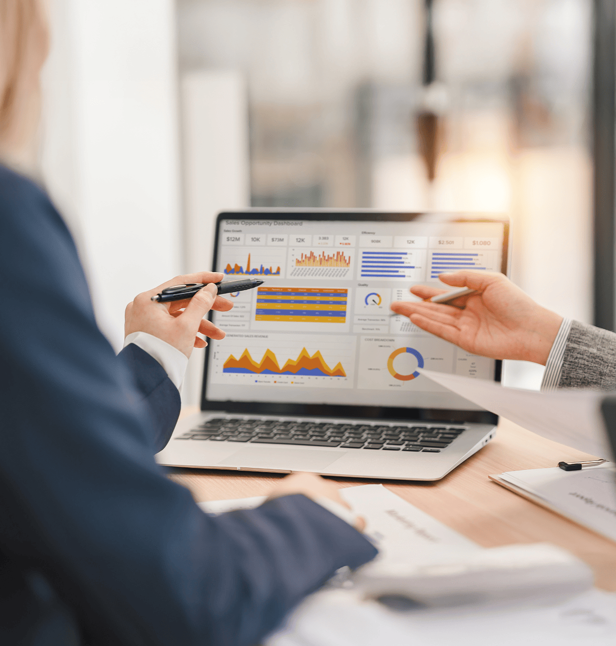 Business professionals discussing data on a laptop screen.