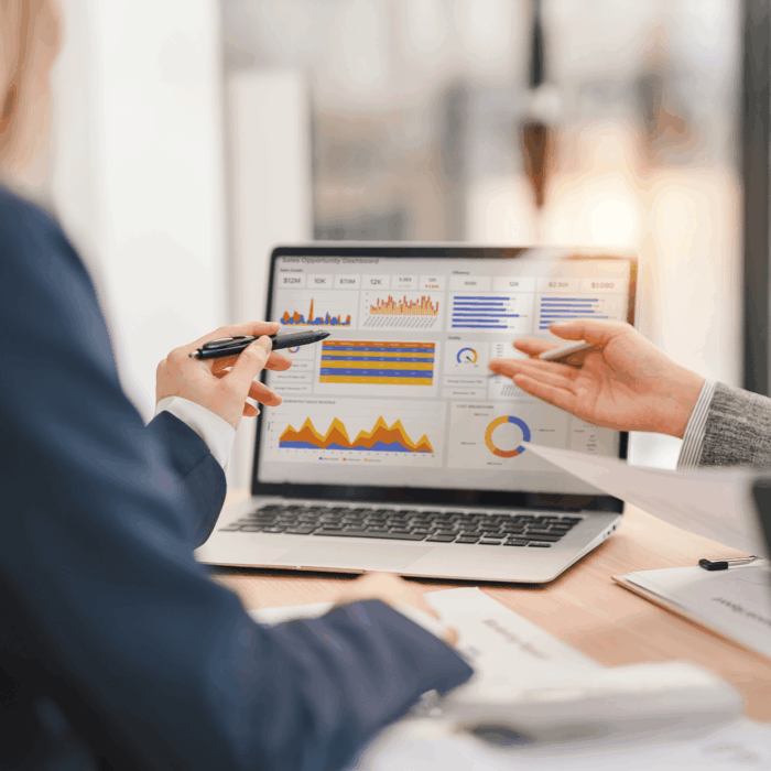 Business professionals discussing data on a laptop screen.