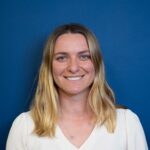 Smiling woman with long hair against a blue background.