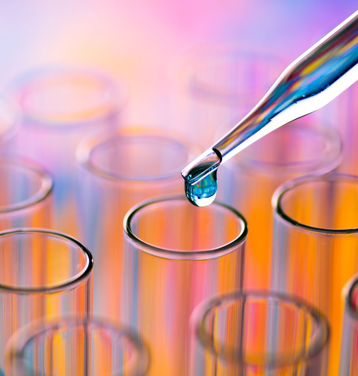 Dropper releasing a droplet into clear test tubes.
