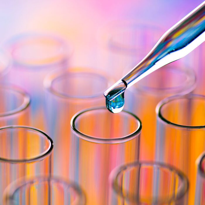 Dropper releasing a droplet into clear test tubes.