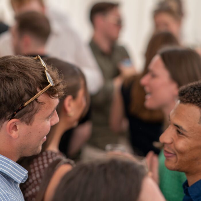 Two friends smiling and chatting at a social gathering.