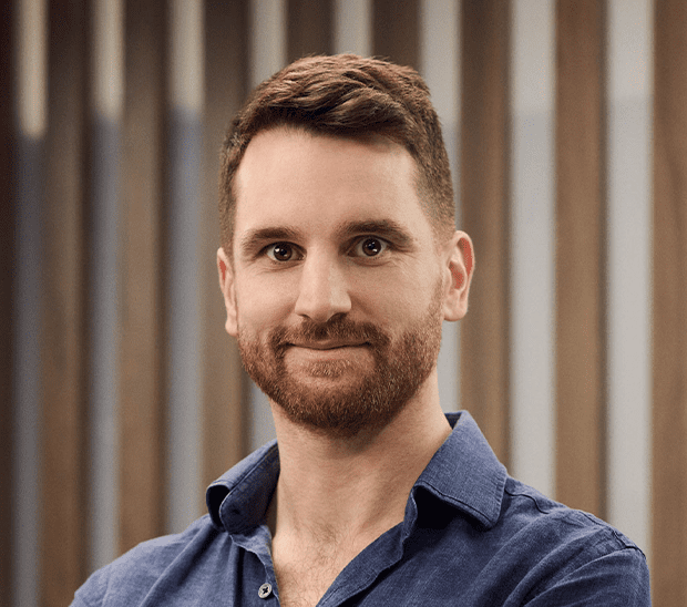 Smiling man with a beard wearing a blue shirt.
