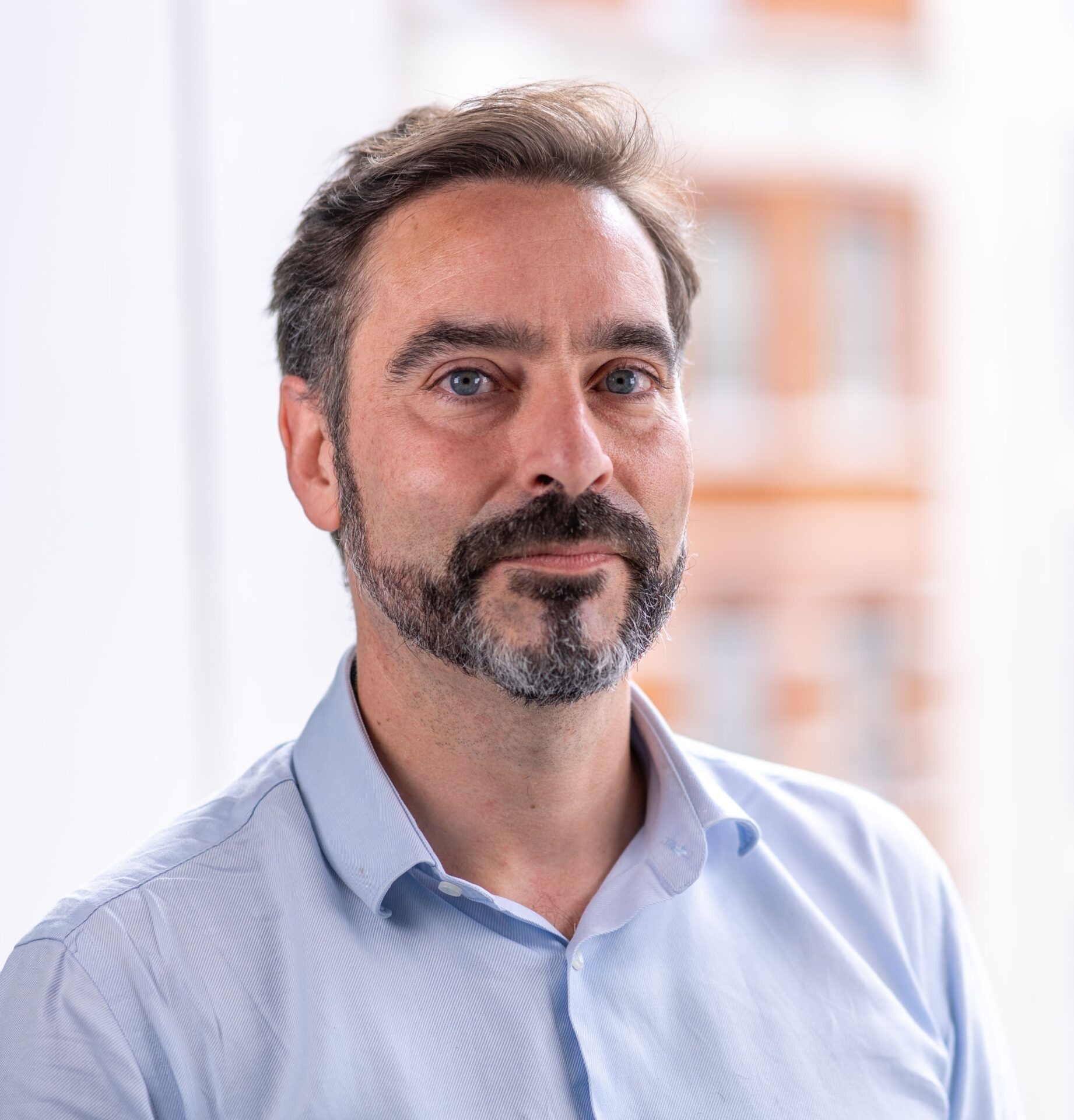 Man with a beard, wearing a light blue shirt.