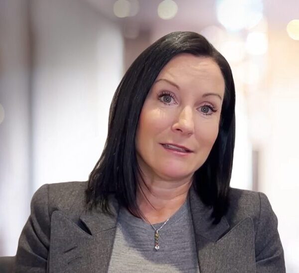 Professional woman with shoulder-length black hair speaking.